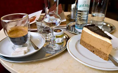 Kawa, szklanka wody i kawałek tortu na marmurowym stoliku wiedeńskiej Café Museum