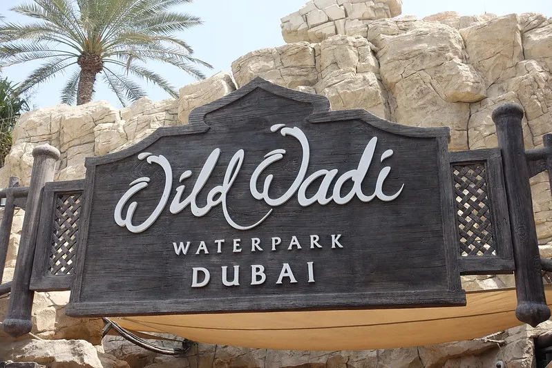 Drewniany szyld z napisem Wild Wadi Waterpark Dubai na tle sztucznych skał