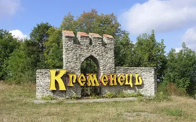 Kamienny znak powitalny w kształcie bramy zamkowej z żółtym napisem Krzemieniec (Кременець)