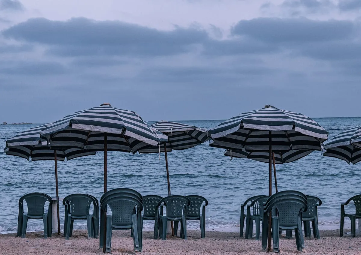 Parasole w biało-zielone pasy i plastikowe krzesła na plaży w Marsa Matruh nad Morzem Śródziemnym