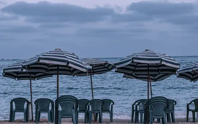 Parasole w biało-zielone pasy i plastikowe krzesła na plaży w Marsa Matruh nad Morzem Śródziemnym