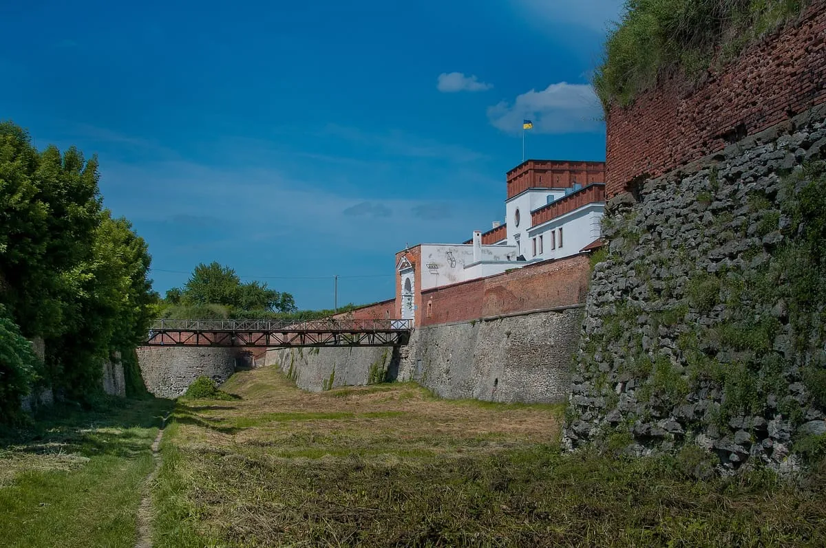 Mury i bastion zamku w Dubnie od strony suchej fosy, w głębi most i budynek bramy