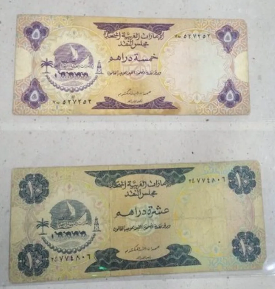 Dwa stare banknoty Zjednoczonych Emiratów Arabskich: 5 dirhamów (fioletowy) i 10 dirhamów (zielony) z wizerunkiem łodzi i palmy