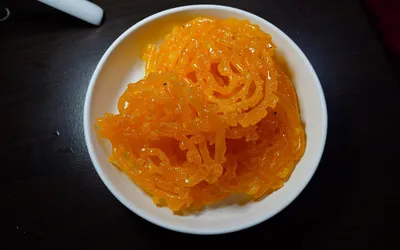 Pomarańczowe, nasączone syropem spiralki zlabii na białym talerzu